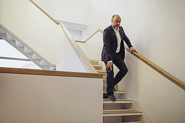 Ein Mann geht die Treppe herab und h&auml;lt sich dabei sein schmerzendes Knie
