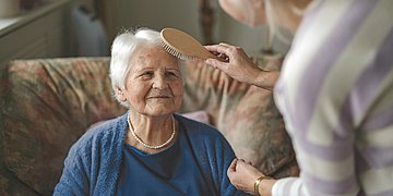 Eine Frau kämmert einer älteren Frau die Haare.
