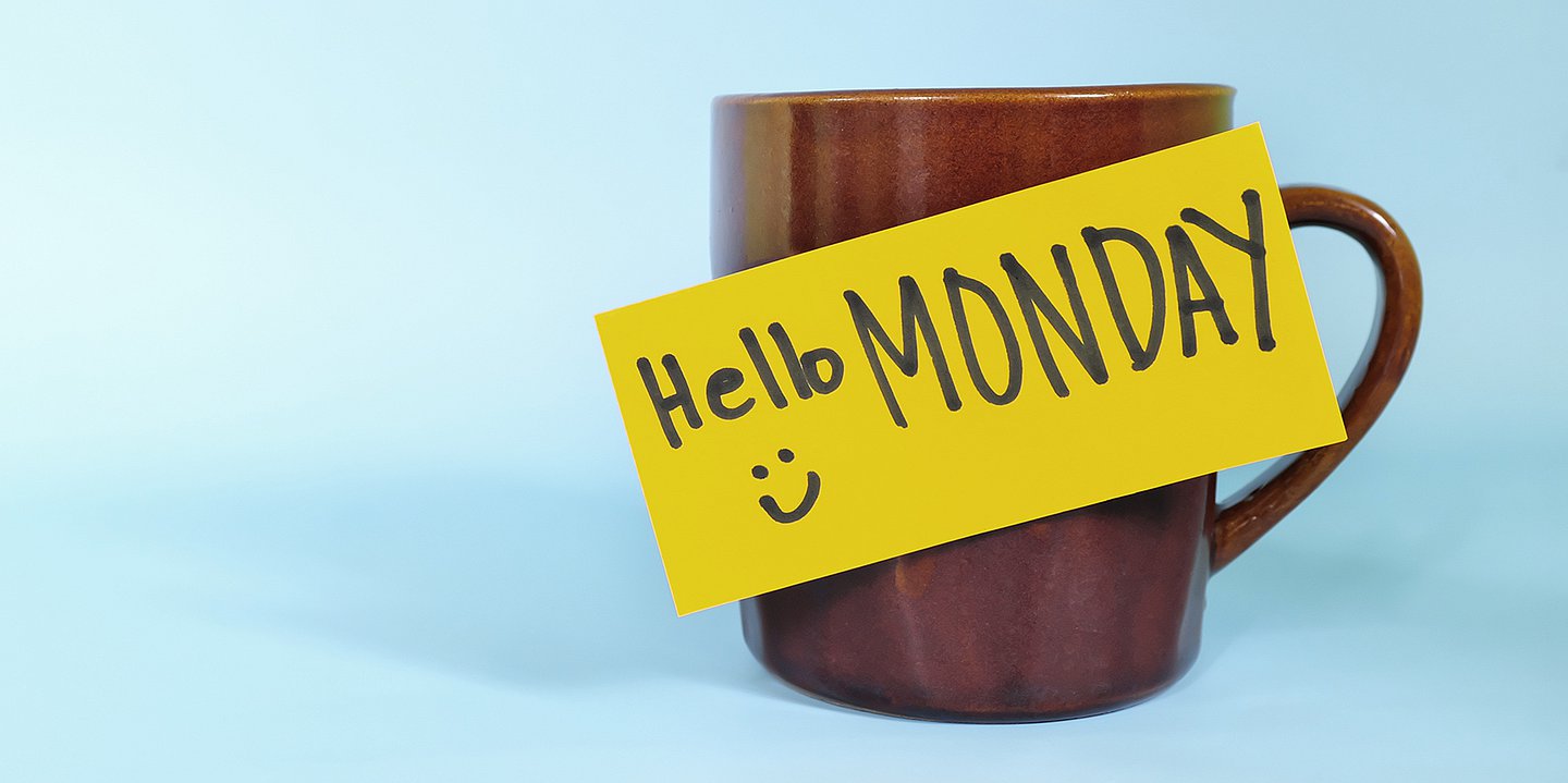 Foto: Auf einer rotbraunen Tasse klebt ein gelbes Post-it mit der Aufschrift "Hello Monday".