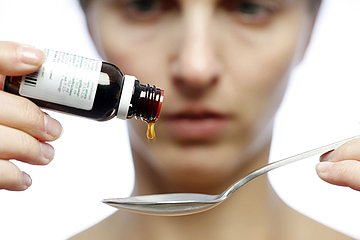Eine Frau tropft sich Medizin auf einen Löffel