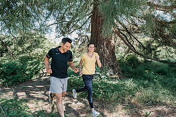 Ein Mann und eine Frau joggen im Wald