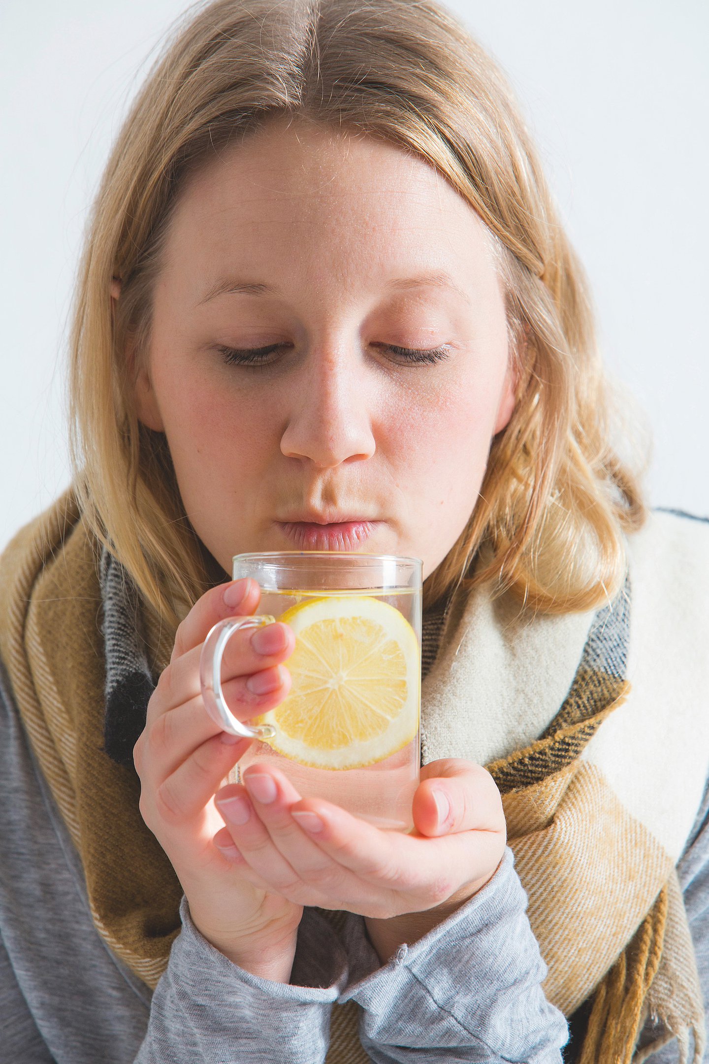Foto: Eine Frau trinkt Heiße Zitrone aus einer Tasse.