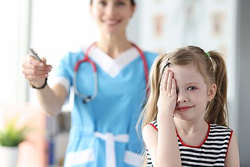 Schulstart in Schleswig-Holstein Ein Mädchen in Nahaufnahme beim Augenarzt hält sich ein Auge bei einem Sehtest zu.