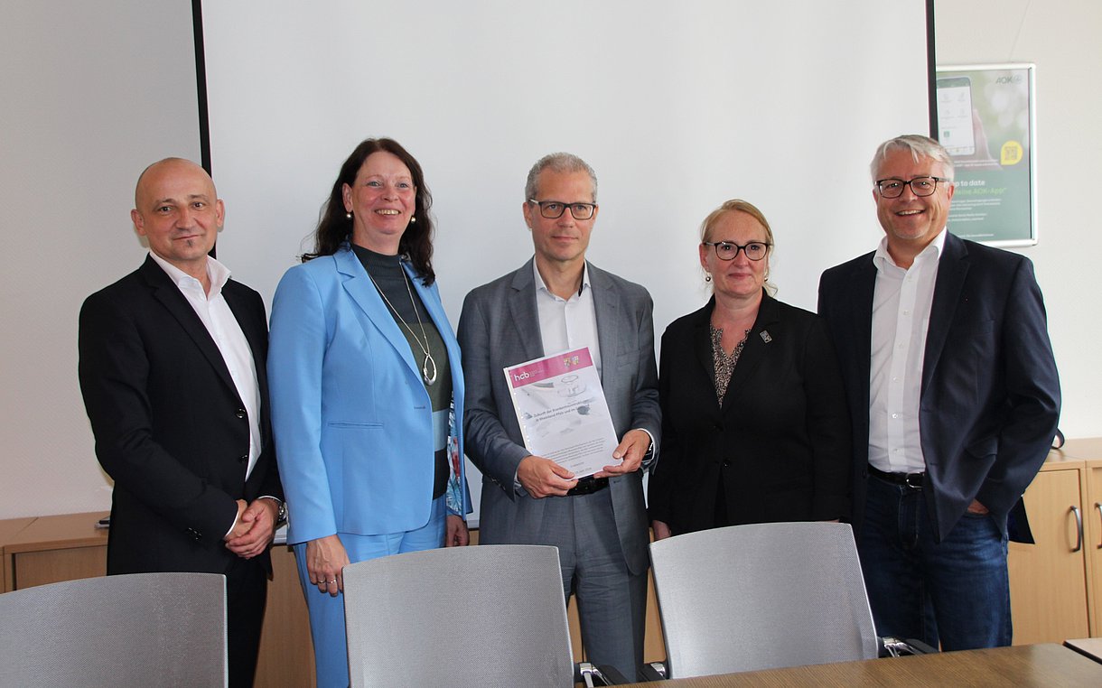 Das Foto zeigt eine fünfköpfige Personengrupe aus zwei FRauen und drei Männern. Die mittlere Person hält das präsentierte Gutachten in den Händen.