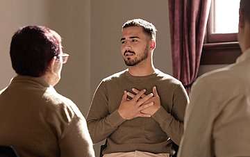 Einsamkeit Mann in einer Selbsthilfe-Gruppe. der seine Hände vor der Brust übereinandergelegt hat