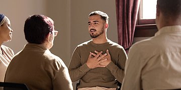 Einsamkeit Mann in einer Selbsthilfe-Gruppe. der seine Hände vor der Brust übereinandergelegt hat