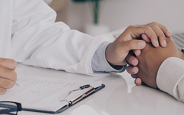 Ein Arzt h&auml;lt die Hand vom Patienten.