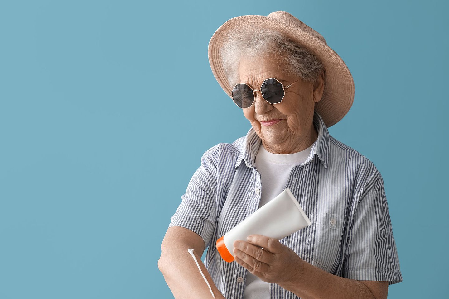 Schmuckbild zeigt Seniorin, die sich mit ausreichend Sonnenschutzmittel eincremt