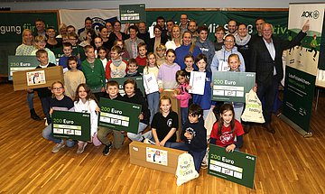 Ehrung Laufabzeichen-Wettbewerb Die Kinder der 22 lauffreudigsten Gewinnerschulen halten strahlend ihre Gewinne und Urkunden in die Kamera.