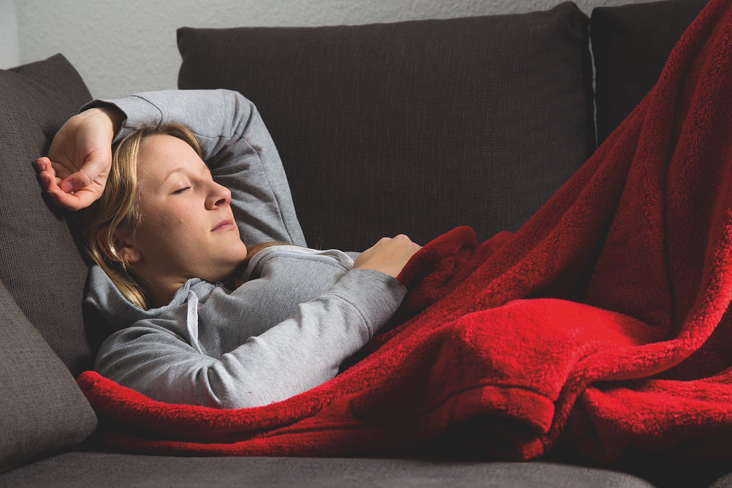 Eine erkältete Frau schläft auf einer Couch