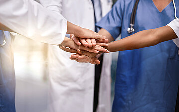 Viele unterschiedliche Menschen legen ihre H&auml;nde aufeinander und symbolieren damit, dass sie gemeinsam ein starkes Team sind, und zwar unabh&auml;ndig davon woher sie kommen, wie alt sie sind und welche Ausbildung sie haben.