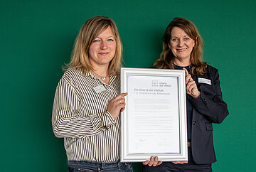 Iris Kr&ouml;ner und Nadine Minak halten die unterzeichnete Charta in den H&auml;nden.