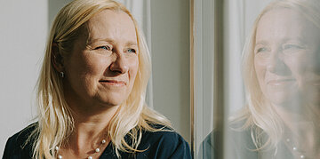 Halbtotale: Diana Stolz schaut aus dem Fenster.