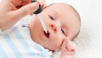 Rotavirus-Fälle in Schleswig-Holstein Ein Säugling auf einer Unterlage liegend, erhält mit einer Pipette eine Flüssigkeit in den geöffneten Mund getröpfelt.
