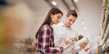 Zöliakie - Glutenunverträglichkeit Eine Frau und ein Mann schauen bei dem Einkauf auf die Liste mit den Inhaltsstoffen.