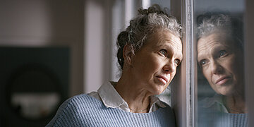 Frau mittleren Alters, die entleert aus dem Fenster blickt