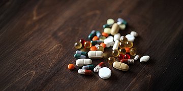 Antibiotika-Resistenzen Auf einem Tisch liegen viele verschiedene bunte Pillen.