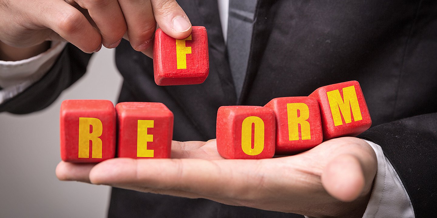 Symbolbild einer flachen Hand, auf die Bauklötze gelegt werden, die mit einzelnen Buchstaben bedruckt sind und das Wort Reform ergeben.