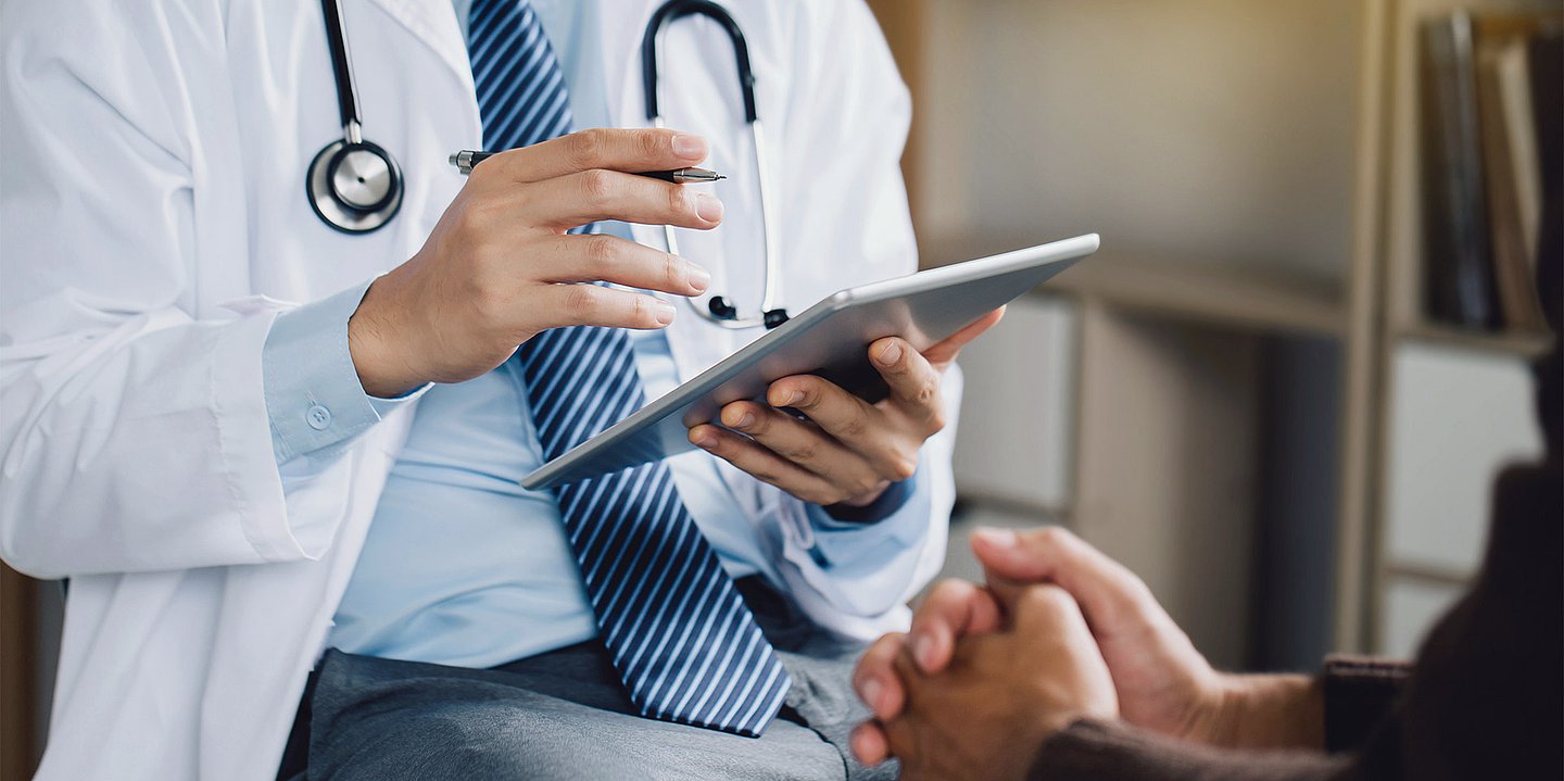 Ein Arzt hält ein Tablet in der Hand.