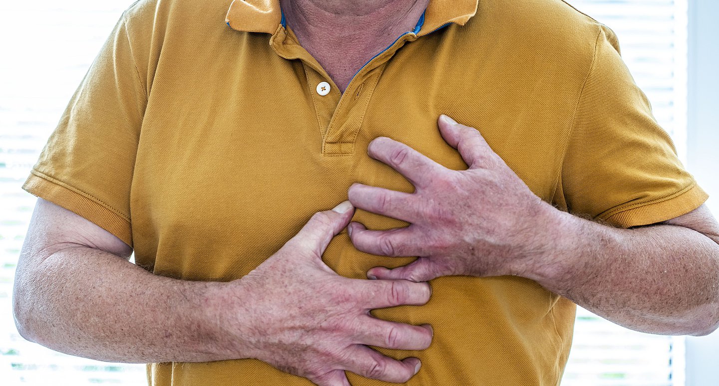 Foto: Ein Mann fasst sich verkrampft an die Brust.