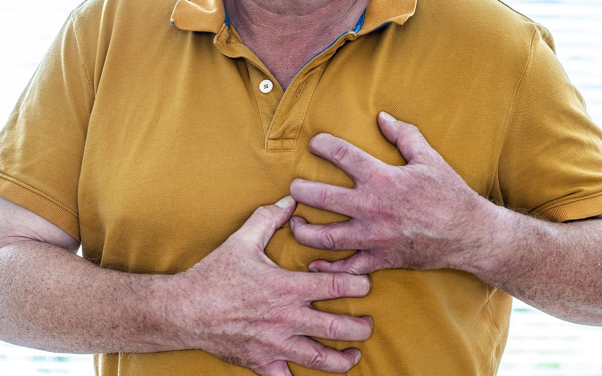 Foto: Ein Mann fasst sich verkrampft an die Brust.