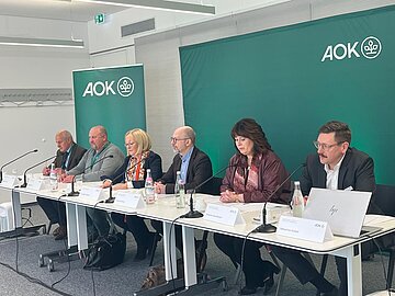 Foto zeigt sechs Teilnehmende beim Pressegespr&auml;ch "Behandlungsfehler: Bilanz aus 25 Jahren AOK-Patientenberatung in Bayern"