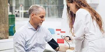 Foto: Eine &Auml;rztin misst den Blutdruck bei einem Patienten.