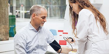 Blutdruck messen Foto: Eine Ärztin misst den Blutdruck bei einem Patienten.