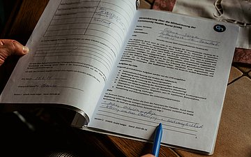 Gesundheitsnetz Foto von Person, die einen Hefter mit Notizen zur häuslichen Situation in der Hand hält. Man sieht nur die Hände.