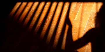 Foto: Schatten einer Frau, die sich an Streben festhält.