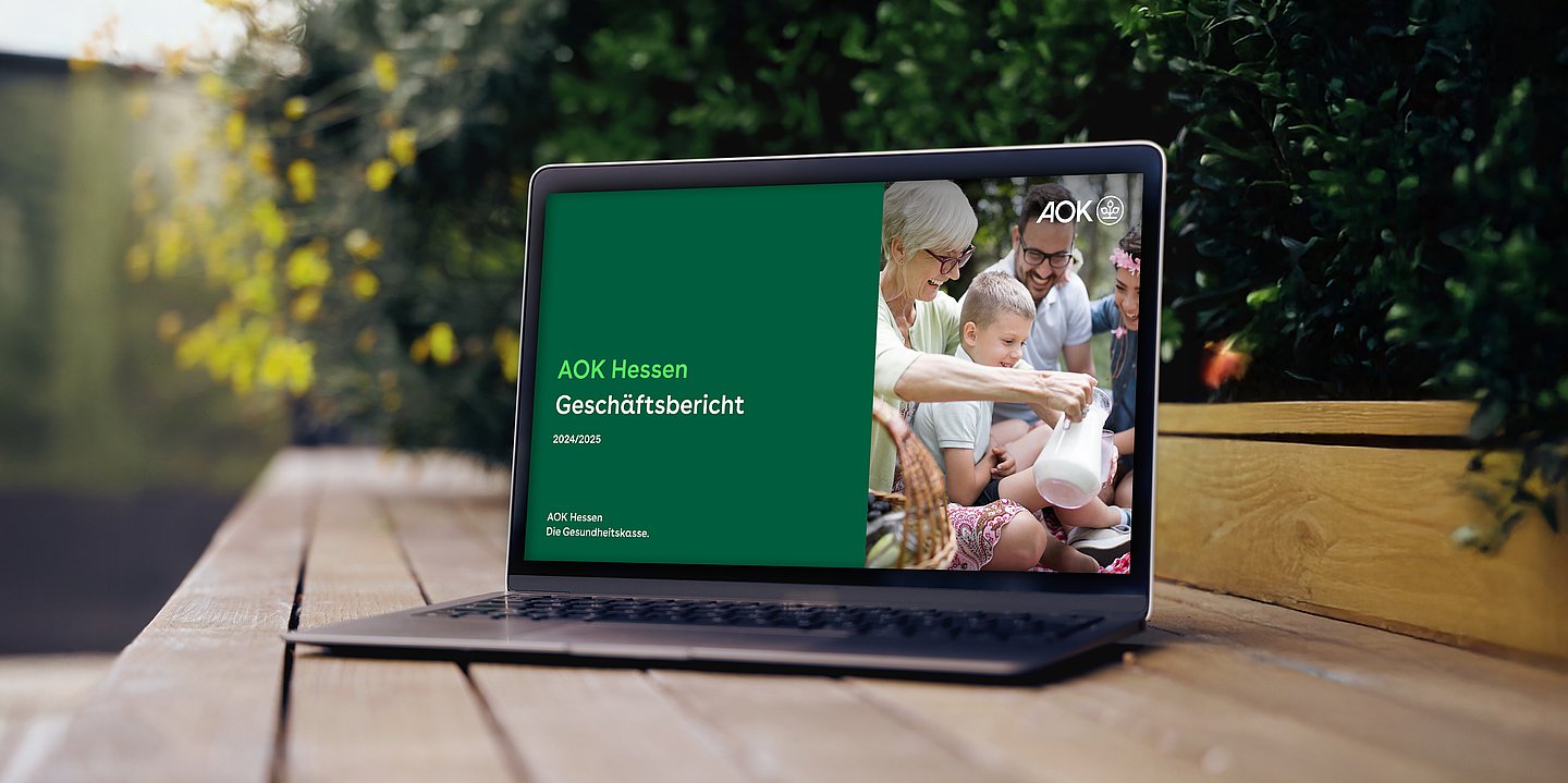 Bildmontage zeigt einen Laptop im Park, in dessen Monitor das Titelbmotiv des Geschäftsberichtes zu sehen ist.