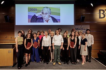 Gruppenfoto mit Jury, Preistr&auml;gerinnen und Preistr&auml;ger sowie Laudatorinnen und Laudatoren des Dr. Georg Schreiber-Medienpreis 2025 mit der Vorstandsvorsitzenden der AOK Bayern, Dr. Irmgard Stippler 