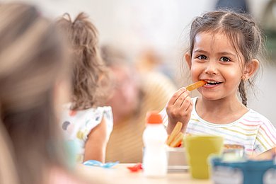 Foto: Ein M&auml;dchen isst w&auml;hrend des Fr&uuml;hst&uuml;cks in der Kita eine geschnittene M&ouml;hre.