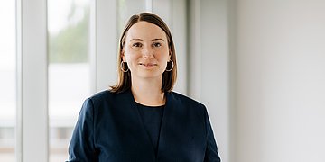 Frau Schenk schaut frontal in die Kamera, hinter ihr ist ein Fenster.