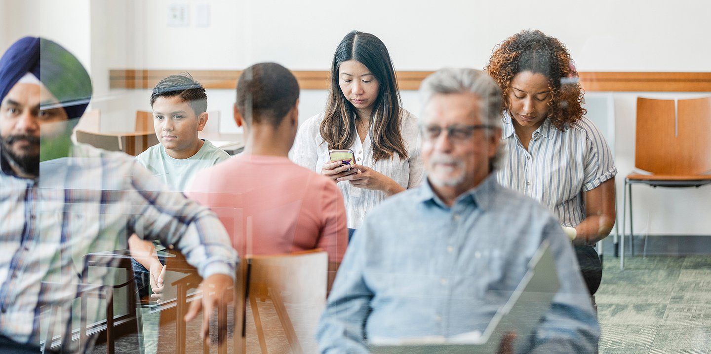 Foto: Mehrere Menschen sitzen gemeinsam in einem Wartezimmer.