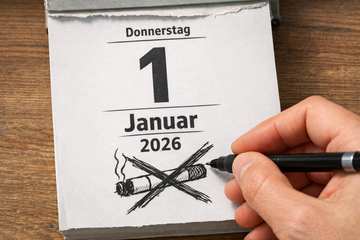 Eine Hand, die einen Stift h&auml;lt, hat auf das Kalenderblatt zum 1. Januar 2026 eine durchgestrichene Zigarette gekritzelt.