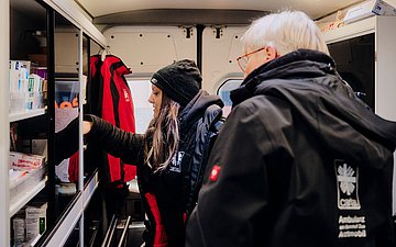 Pflegefachkraft Raber und Ärztin Dr. Burkhardt auf der Suche nach dem passenden Verband im Arztmobil.