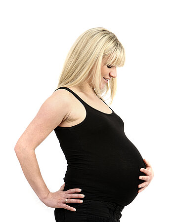 Eine schwangere Frau h&auml;lt ihren Bauch.