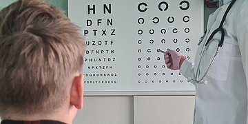 Ein Junge macht ein Sehtest, ihm gegenüber steht eine Ärztin.