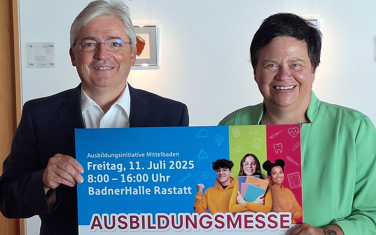 Ulrich Kistner und Petra Spitzmüller halten gemeinsam ein Plakat der Ausbildungsmesse Mittelbaden in die Kamera.