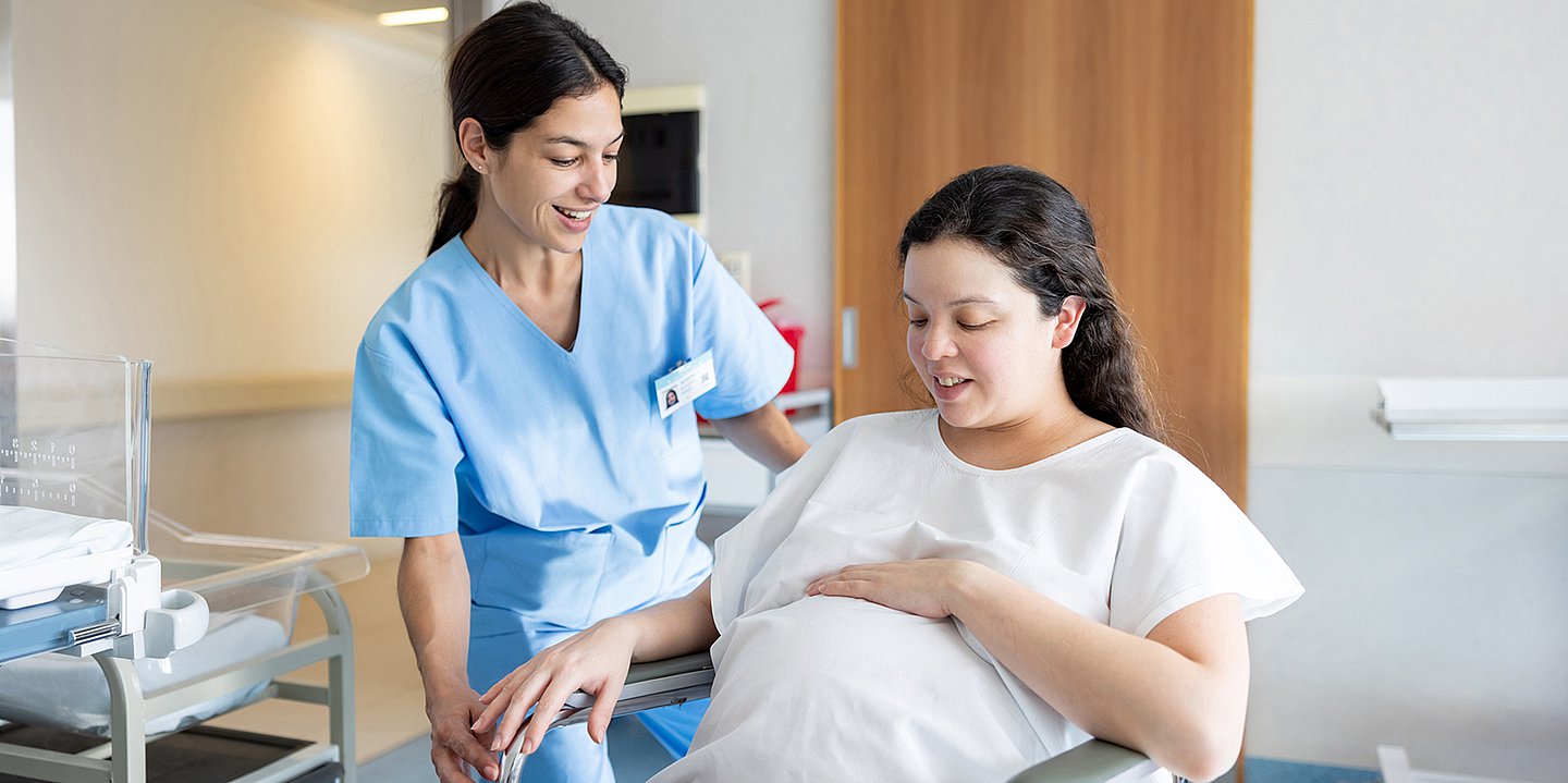 Foto: Eine Hebamme kümmert sich um eine hochschwangere Frau.