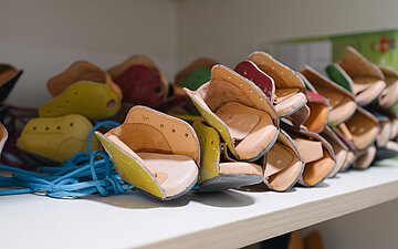 In einem Regal liegen viele Spezialschuhe zur Behandlung von Klumpf&uuml;&szlig;en.
