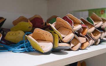 In einem Regal liegen viele Spezialschuhe zur Behandlung von Klumpfüßen.