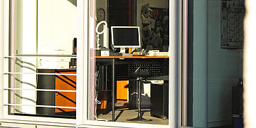 Foto von einem menschleeren Arbeitsplatz, von drau&szlig;en durch das Fenster fotografiert
