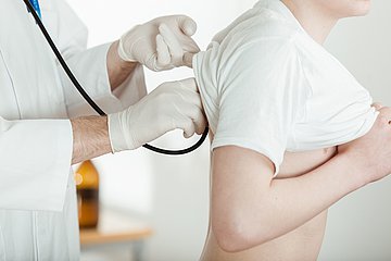 Gesundheits-Check für Jugendliche Ein Arzt führt bei einem Teenager einen Gesundheits-Check durch.