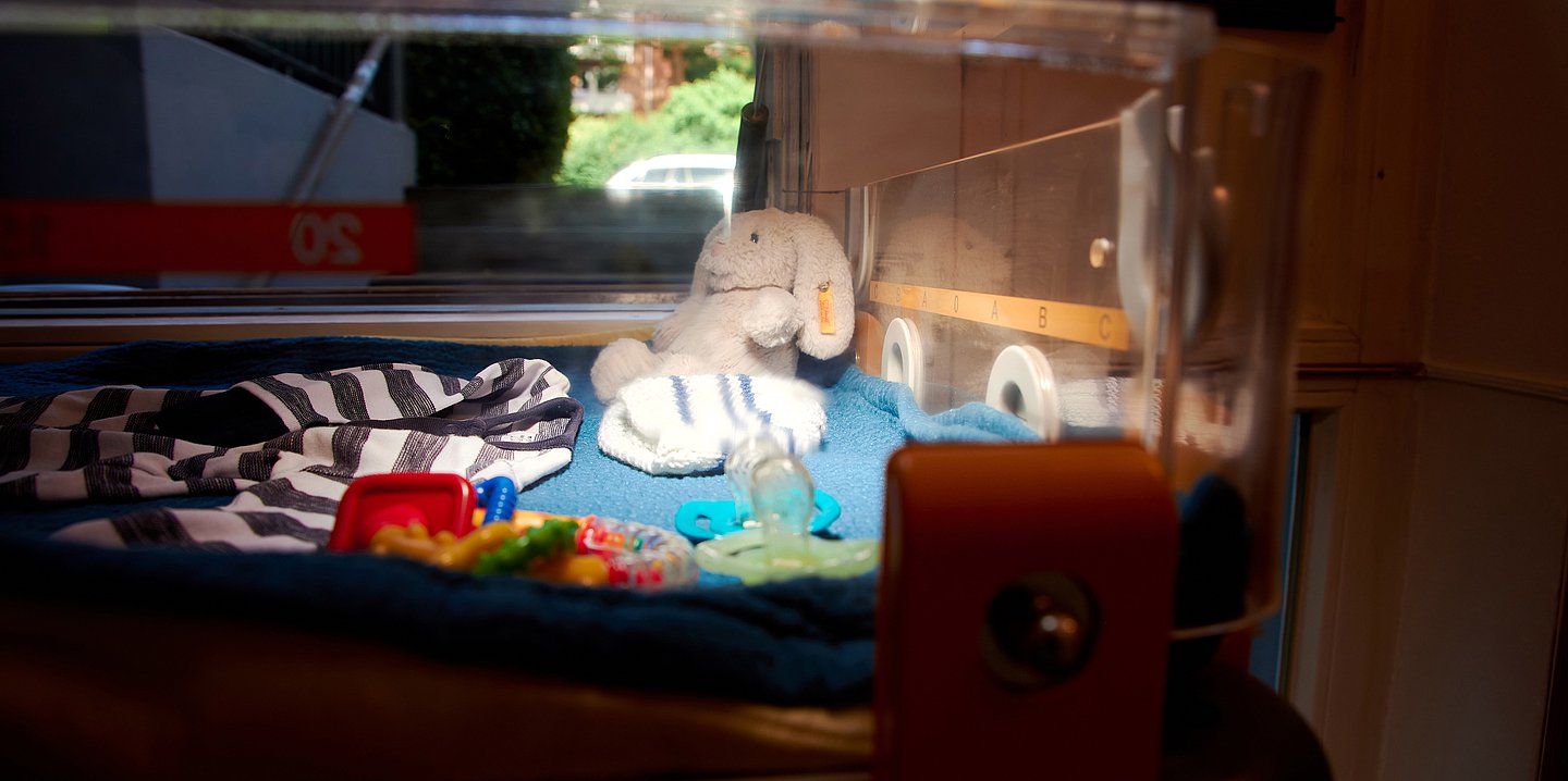 Ein Wärmebett im Innenraum der KiTa. In ihm liegen ein Kuscheltier, ein Schlafsack, Spielzeug und Schnuller.