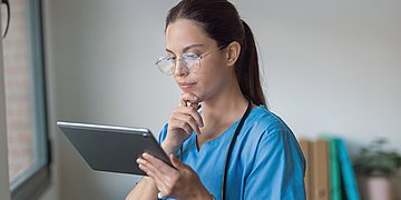 KIM-Nutzung in der Pflege Eine Pflegekraft schaut sich Daten auf einem Tablet an.