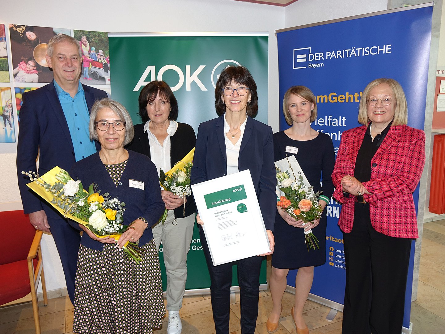 Foto zeigt Übergabe des Qualitätszeichens stellvertretend für alle ausgezeichneten Einrichtungen an das Mutter-Kind Kurhaus am Kurpark in Bad Königshofen durch Dr. Irmgard Stippler, Vorstandvorsitzende der AOK Bayern (ganz rechts im Foto). Weiter im Foto von links nach rechts: AOK Direktor Frank Dünisch, Regina Behrendt (Therapeutische  und Pädagogische Leitung), Dr. med. Marianne Heusinger (Ärztliche Leitung),  Evi Bindrim (Geschäftsführerin und Klinikleitung) und Nicole Schmidt (Verwaltungsleitung).