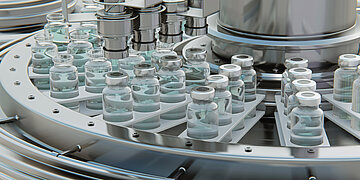 Auf einer Haltevorrichtung stehen kleine Flaschen, die mit Impfstoffen gef&uuml;llt sind. Eine Maschine verschlie&szlig;t die Flaschen.