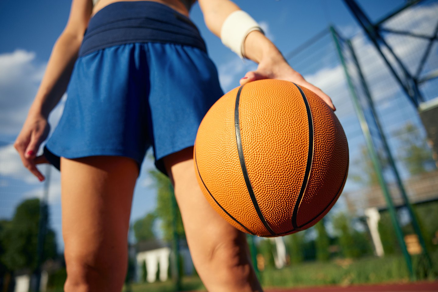 Ein Mädchen in Nahaufnahme hält einen Basketball auf einem Outdoor-Spielfeld.